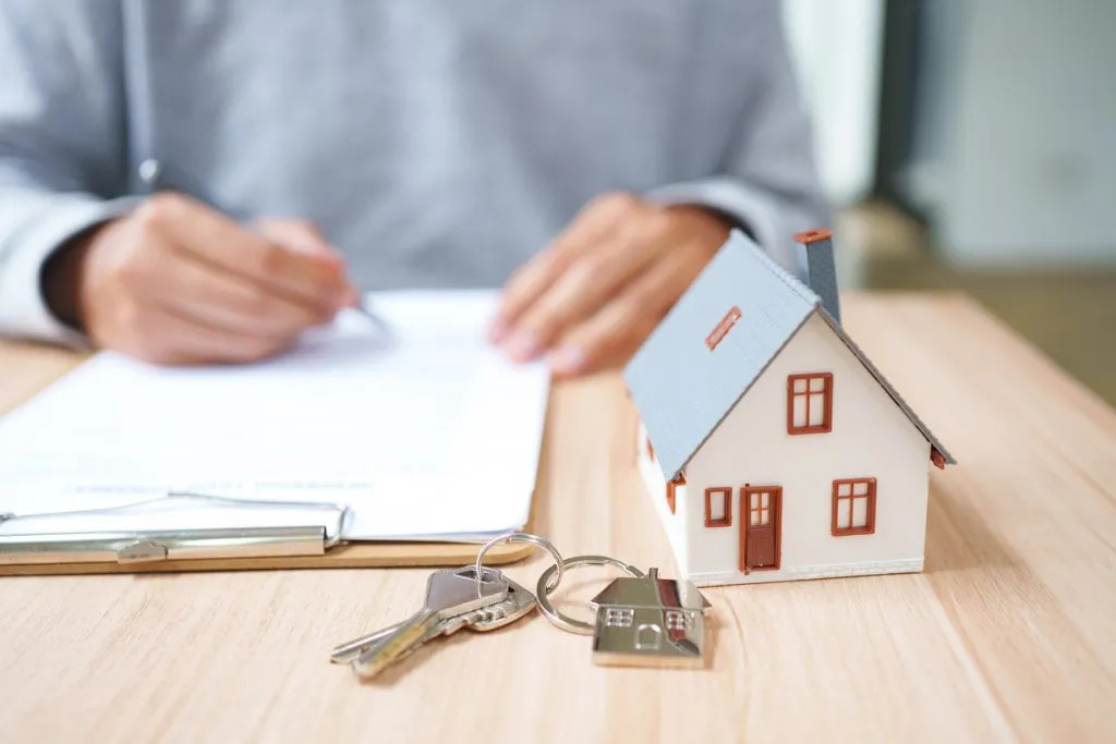 Property agreement signing with house model and keys for title and closing services