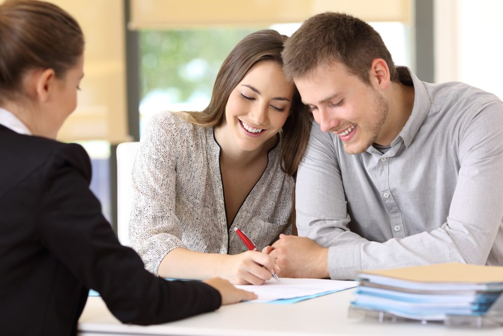 Happy couple signing papers together at a real estate closing
