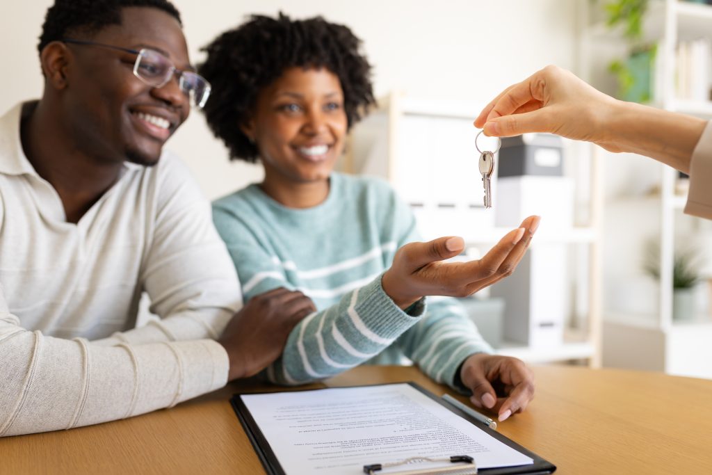 Happy couple receiving keys from real estate agent after closing on a home