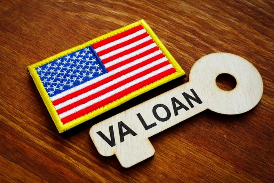 American flag badge next to VA LOAN key cutout on wooden surface